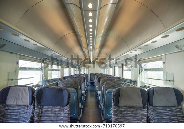 Empty rail passenger carriage seat rows with\
dimishing perspective