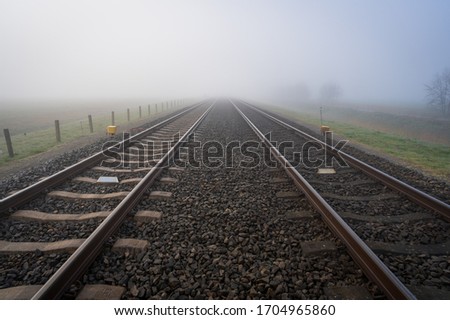 Empty railroadtracks disappearing into the spring fog.