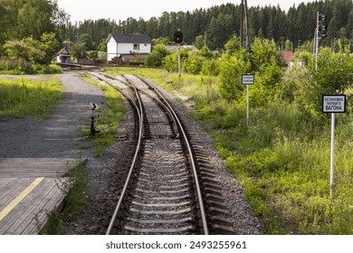 An empty railway track turning left with a railway switch, white traffic signs have Russian text, which means: Locomotive Stop,  First Car Stop - Powered by Shutterstock