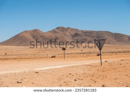 empty ravel road with signs by sunny day in desert of Namibia