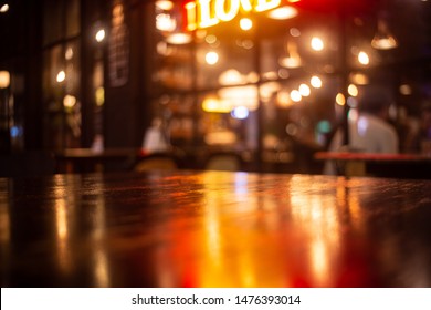 Empty Real Wood Table Top With Light Reflection On Scene At Restaurant, Pub Or Bar At Night. Blurred Background For Product Display Or Montage Your Products With Several Concept Idea And Any Occasion.