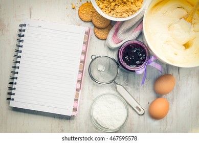 Empty Recipe Notebook With Cheese Cake Ingredients Prepared Over A White Wood Background. 