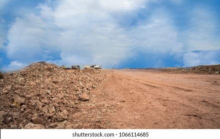 Empty Reclamation And Compact Land And Dump Truck Carrying Red Soil On Construction Site With Blue Sky. Land Plot For Sales And Real Estate Development Project Concept Background.