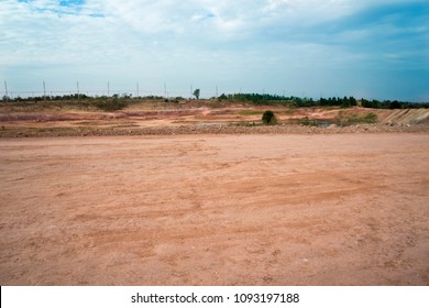 Empty Reclamation, Compact Land And Lake Or Water Reservoir, Red Soil On Construction Site With Blue Sky. Land Plot For Sales And Real Estate Development Project Concept Background