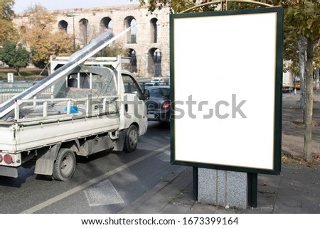Empty rectangular bilboard. Photographed on the edge. There is an iron profile on the trucker on the road.