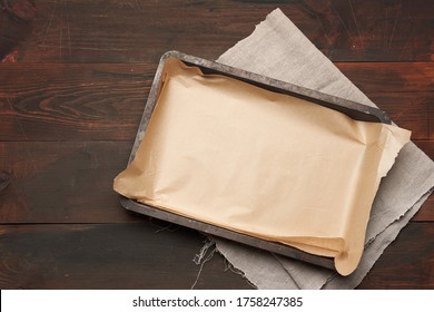 empty rectangular metal pan covered with brown parchment paper on a wooden table, top view