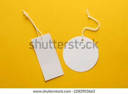 Empty rectangular and round white price tags with string on yellow background. Template for design