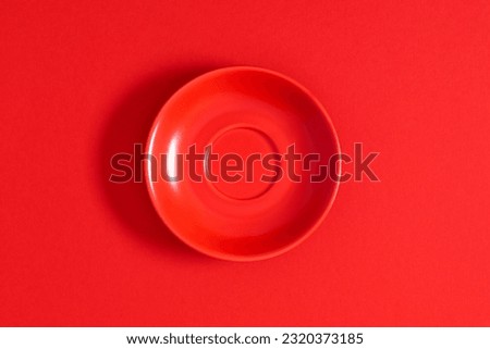 Empty red ceramic round plate isolated on red background. Flat lay, top view, copy space