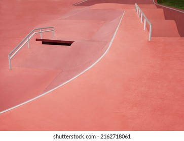 Empty Red Colored Skatepark With Pump Track And Rail