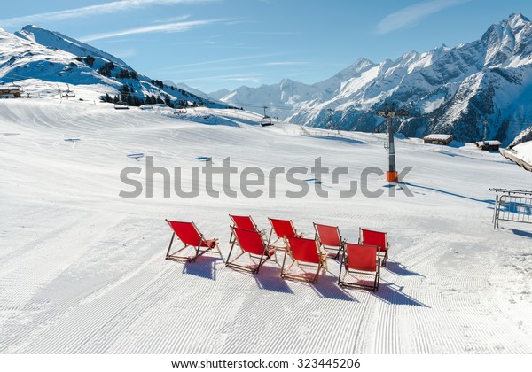 Empty red deck chairs on the snow in Mayrhofen ski\
resort, Austrian Alps
