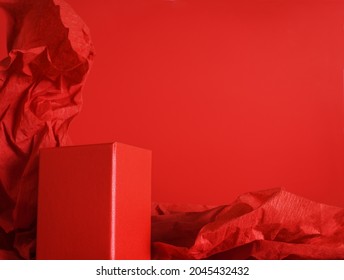Empty red rectangular podium on red background with crumpled crepe paper
