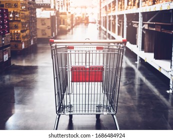 Empty Red Shopping Cart Trolley In Super Market Store Aisle Representing Stocking Products, Buying Food Hording Supplies For Storing Food In Home Or Small Retail Shop, Purchasing Goods And Produce 