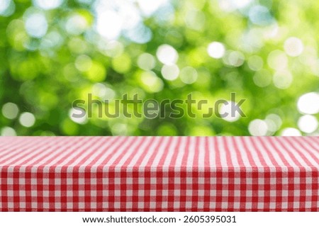 Empty red and white checkered tablecloth for picnic over blurred green background 