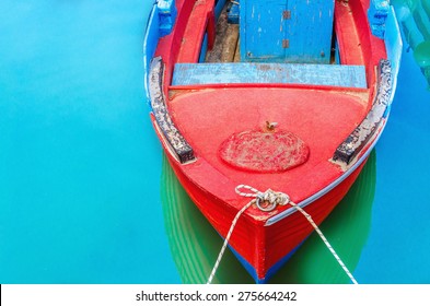  Empty red wooden boat with blue broadside moored in port with silent azure water