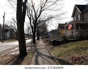 Empty Residential Sidewalk Lined with Trees and Houses During Late Autumn in a Quiet Neighborhood