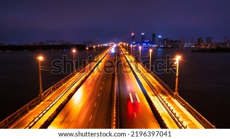 Empty road bridge across the river, night cityscape. There is no traffic.