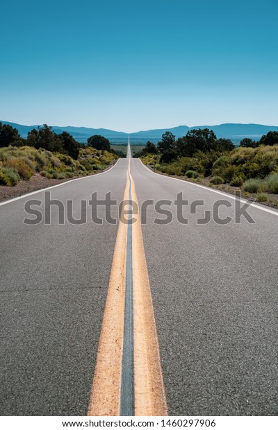 Empty road of\
desert, looking off to the White Mountains of Nevada. Taken in\
California off of State Route\
167
