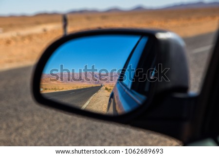 empty road in the desert - view in the car mirror