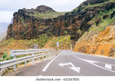 Empty road with the direction of traffic in the green mountains of the Canary Islands, Spain
