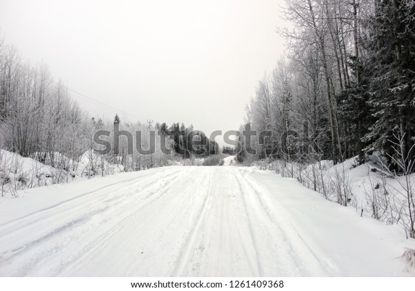 Empty road with huge snow banks on sides on cloudy\
winter day