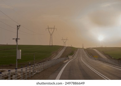 Empty road at sunset in early spring. On the edge of the road a small weather station. A misty, slightly cloudy early spring evening in the hilly suburban areas crossed by an asphalt road.  - Powered by Shutterstock