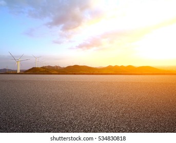 Empty road surface floor with Eco-environmentally friendly power generation of power turbines of green energy on the top of the hill of sunset