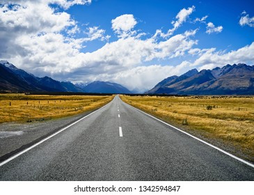 An empty road through the mountain with blue sky background. Concept of traveling on holiday. - Shutterstock ID 1342594847