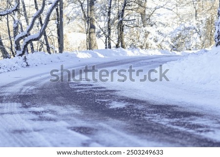 An empty road with a tricky right turn covered with snow. Road trip, extreme driving, safety on the roads, and environmental conservation.