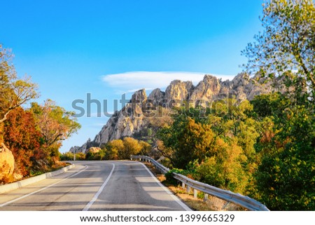 Empty road without cars, in Sardinia Island in Italy in summer. Panorama with highway and green nature and blue sky. Mountains on the background.