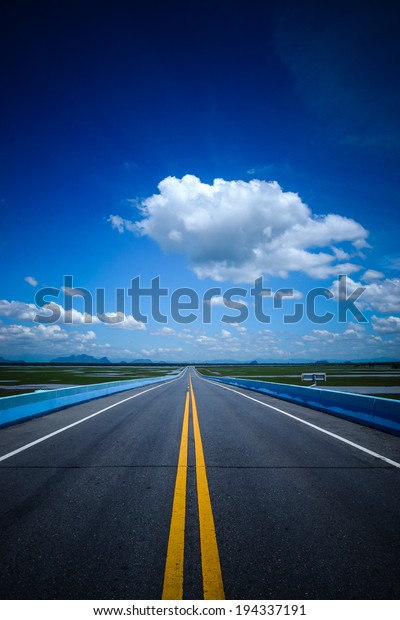 Empty\
road and the yellow traffic lines with blue\
sky.