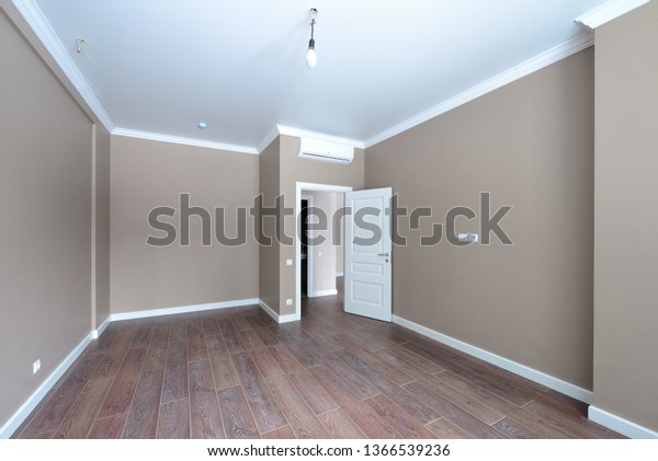 Empty room after repairs in an\
apartment building. Fresh renovated room with wooden\
floor