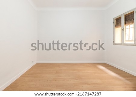 Empty room with aluminum window with shutter half up, wooden floorboards and plain white painted walls