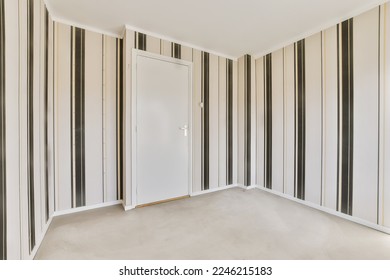 an empty room with black and white striped wallpapers on the walls there is a door in the corner