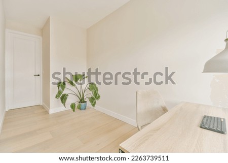 an empty room with a desk, chair and plant in the corner on the right hand side of the room