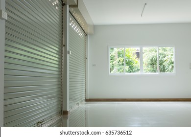 Empty Room In House Residential Building With Aluminium Roller Shutter Door Closed And Glass Window Sliding And White Flooring Tile