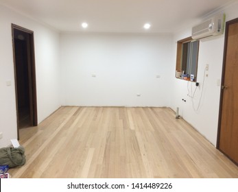 An empty room interior in the middle of a house renovation with modern down lights shining of an Australian hardwood timber floor and white walls and wooden doorways and frames in Victoria Australia