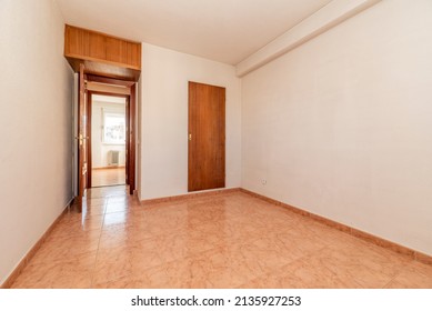 Empty Room With Orange Stoneware Floor, Mahogany Wood Door And White Painted Walls And Brass Door Handle On Built In Wardrobe And Trunk