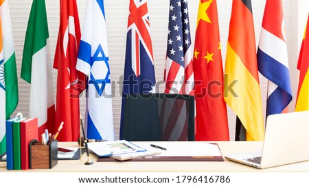 Empty room for president or government statesman with laptop, year planner, business charts and diagram, pen on wooden table and various international flag. Country Leader Room with flags. Press room.
