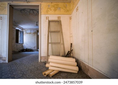 In an empty room, a stack of papers is placed on the bare floor. The room is devoid of any other objects or furniture, creating a minimalist setting