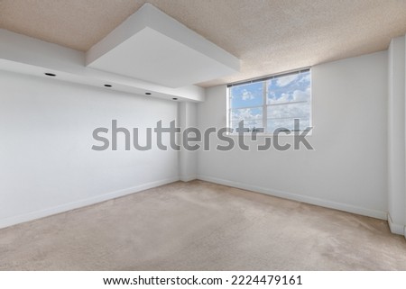 Empty room with window with sky in the background, white walls, carpeted floor and beige ceiling, wall with 4 lights, ideal shot for office or bedroom rendering