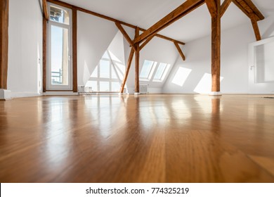 empty  room with wooden floor and roof beams - penthouse