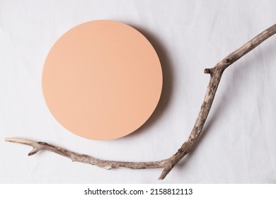 Empty round beige platform podium and dry tree twigs on white linen fabric background. Minimal creative composition background for cosmetics or products presentation. Top view