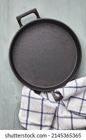 Empty Round Cast Iron Pan, Tea Towel On A Light Blue Wooden Table. Mockup For Laying Out Food