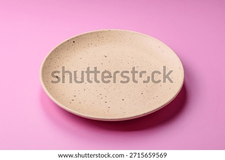 An empty round ceramic plate on a pink background as a kitchen utensil. An empty plate as a food background for your design