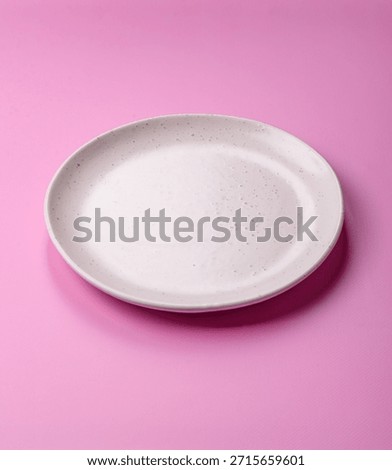 An empty round ceramic plate on a pink background as a kitchen utensil. An empty plate as a food background for your design