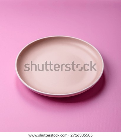 An empty round ceramic plate on a pink background as a kitchen utensil. An empty plate as a food background for your design