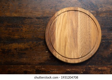 Empty round cutting board on a wooden table. Space for text. Top view.