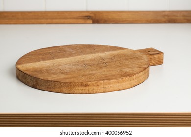 Empty round cutting board on a white kitchen top.