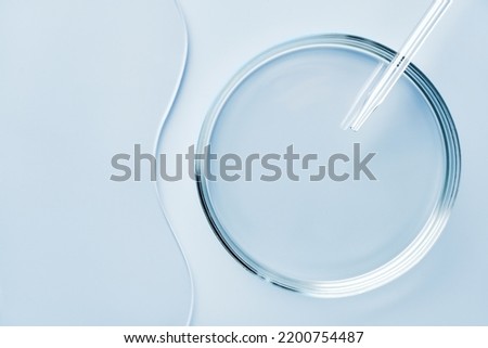 Empty round petri dish or glass slide and Pipette on blue background. Mockup for cosmetic or scientific product sample