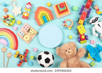 Empty round platform podium stand, with teddy bear, robot and many natural wooden ecological sustainable educational children toys. Baby kid toys on light blue background. Top view, flat lay